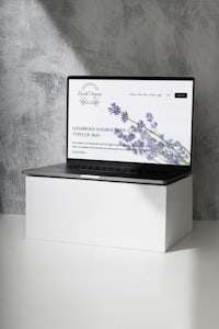 a laptop is sitting on a white box with lavender flowers on it